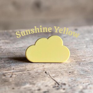 May include: A solid, matte, sunshine yellow cloud-shaped object with smooth, rounded edges. The text "Sunshine Yellow" is printed in a light yellow font above the cloud shape, which features a flat base and a curved, multi-lobed top.
