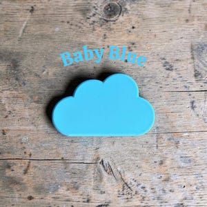 May include: A solid, flat, baby blue cloud-shaped object with smooth, rounded edges. The text "Baby Blue" is printed in a light blue sans-serif font directly above the cloud shape, centered horizontally against the background.