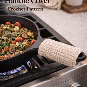 May include: A beige crochet cast iron handle cover on a black cast iron skillet filled with cooked vegetables. The handle cover is protecting the handle from heat. Text on the image reads "Cast Iron Handle Cover Crochet Pattern."
