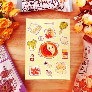 Puede incluir: Un conjunto de pegatinas coloridas que representan varios ingredientes para una comida de olla caliente, incluyendo tofu, fideos, verduras y un caldo rojo. Las pegatinas están sobre un fondo amarillo con líneas de cuadrícula blancas.