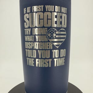 May include: Navy blue insulated tumbler with silver text. The text reads "IF AT FIRST YOU DO NOT SUCCEED TRY DOING WHAT YOUR DISPATCHER TOLD YOU TO DO THE FIRST TIME." A heart-shaped graphic with an American flag design is also featured.