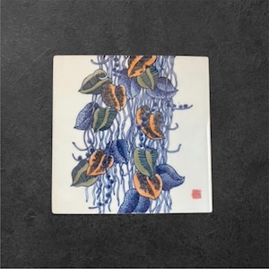 May include: Square ceramic tile with a botanical design. The artwork features blue, orange, and green leaves with blue flowing lines against a white background. A small red stamp is in the lower right corner.