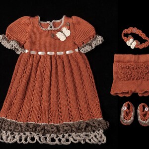 Könnte beinhalten: Handgefertigtes, rostfarbenes Strick-Babykleid-Set. Das Set beinhaltet ein Kleid mit Schmetterlingsapplikation, Shorts, ein Stirnband und passende Schuhe. Das Kleid hat einen wellenförmigen Saum und Ärmel mit grauem Besatz. Maße in cm.