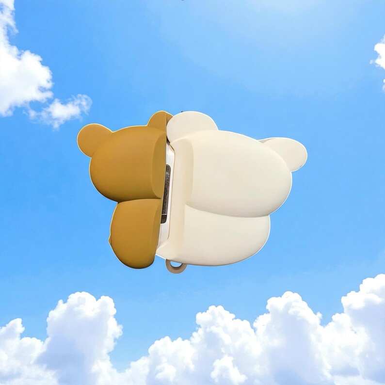 May include: A two-tone bear-shaped phone case, with one side in a light brown and the other in white. The case is designed to fit a phone, with cutouts for the camera and charging port. The background is a bright blue sky with fluffy white clouds.