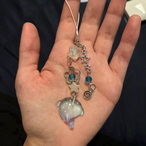 May include: A silver charm bracelet with a blue and white iridescent fish charm, a seashell charm, a star charm, and a blue bead charm.