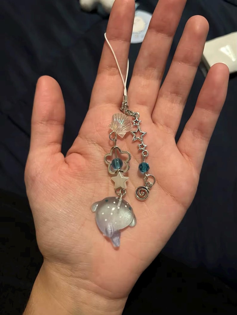 May include: A silver charm bracelet with a blue and white iridescent fish charm, a seashell charm, a star charm, and a blue bead charm.
