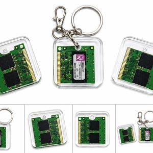 May include: A square keychain featuring a green computer RAM circuit board encased in clear acrylic. The circuit board has two black memory chips and gold contact pins. One keychain includes a metal ring and clasp, while others are shown without.