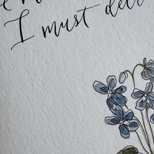 May include: A white textured paper print featuring black calligraphy text that reads "he must increase, I must decrease" positioned above a watercolor illustration of blue and purple flowers with green leaves and thin dark stems.