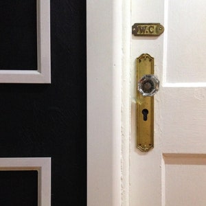 antique brass slightly ornate doorknob escutcheon with keyhole for skeleton key shown on door with antique crystal knob