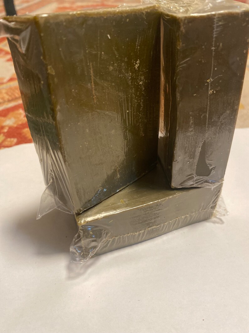 May include: Four olive-green rectangular blocks, wrapped in clear plastic. The blocks are stacked, with two forming a base and two resting on top. The packaging is slightly wrinkled, and the blocks have a slightly rough texture.