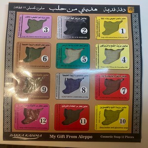 Op de afbeelding: Een set van 12 kleine zeepjes, elk in de vorm van de omtrek van Syri&euml;. De zeepjes zijn gerangschikt in een raster van vier rijen en drie kolommen. Elk zeepje heeft een nummer van 1 tot 12 en een beschrijving van de ingredi&euml;nten van de zeep in het Arabisch. De set is gelabeld met "My Gift From Aleppo" en "Cosmetische Zeep 12 Stuks".