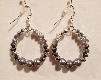 May include: A pair of silver hoop earrings with three silver pearl beads and crystal accents.