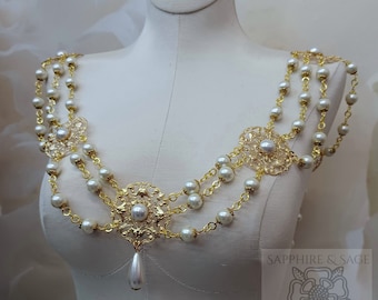 May include: A gold and white pearl necklace with a delicate floral design. The necklace is made of multiple strands of pearls and gold chain, with a large floral pendant in the center. The necklace is displayed on a white mannequin.