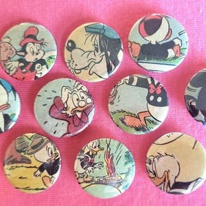 Op de afbeelding: Negen ronde, kleurrijke cartoonfiguur-knoppen. De knoppen tonen personages zoals Donald Duck, Goofy en Mickey Mouse.