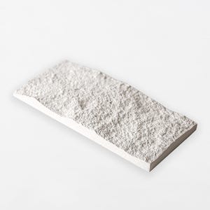 Könnte beinhalten: Eine rechteckige, cremefarbene Steinplatte mit rauer, strukturierter Oberfläche. Die Fliese hat eine leicht unregelmäßige Form und eine saubere, glatte Kante. Der Stein scheint ein dekoratives Element zu sein.