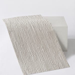 K&ouml;nnte beinhalten: Ein rechteckiger Tischl&auml;ufer in hellem Beige mit einer durchgehenden vertikalen Rippenstruktur. Der Stoff weist eine Reihe paralleler, erhabener Linien auf, die &uuml;ber die gesamte L&auml;nge verlaufen und ein gleichm&auml;&szlig;iges, lineares Muster erzeugen.