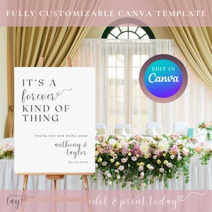 May include: A white sign with black text that reads "It's a forever kind of thing."  The sign also includes the names "Anthony & Taylor" and the date "07.15.2025". The sign is on an easel in front of a table decorated with flowers.