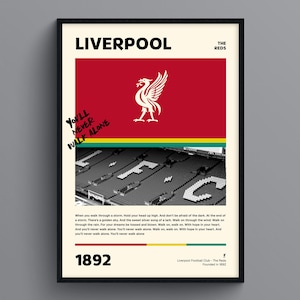 Liverpool FC Poster Framed Print: A framed Liverpool FC poster with the iconic "You'll Never Walk Alone" slogan, team logo, and Anfield stadium image. Perfect decor for soccer fans and Liverpool supporters.
