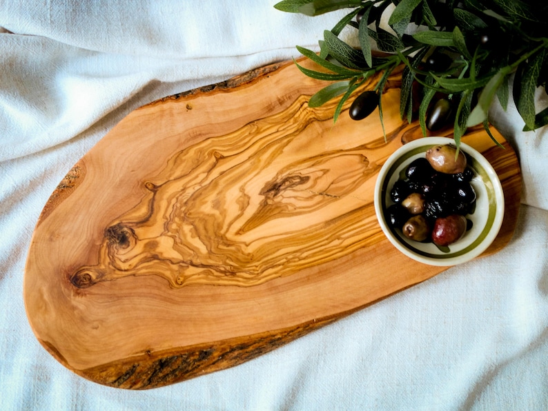 Custom olive wood kitchen board with juice groove and smooth finish. Durable, food-safe, and uniquely engraved for weddings or housewarmings.