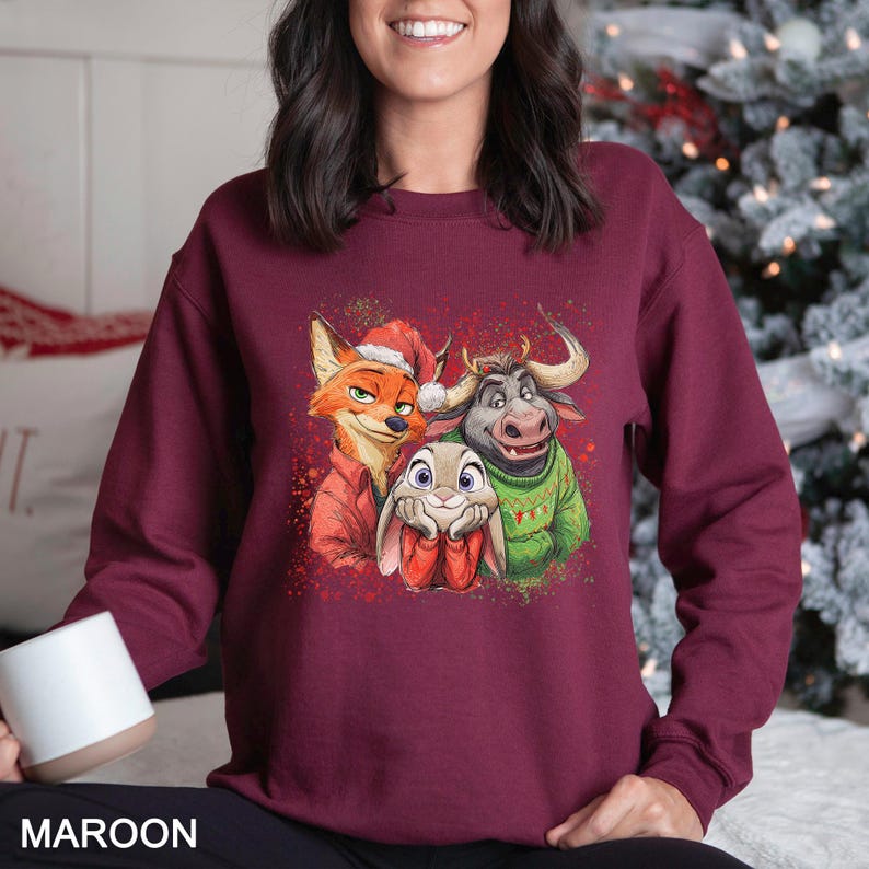 May include: Maroon sweatshirt featuring a festive cartoon graphic of a fox, a bunny, and a bull, all wearing holiday attire. The fox is in a Santa hat, the bunny is in red boots, and the bull is in a green sweater. The word "MAROON" is printed at the bottom.