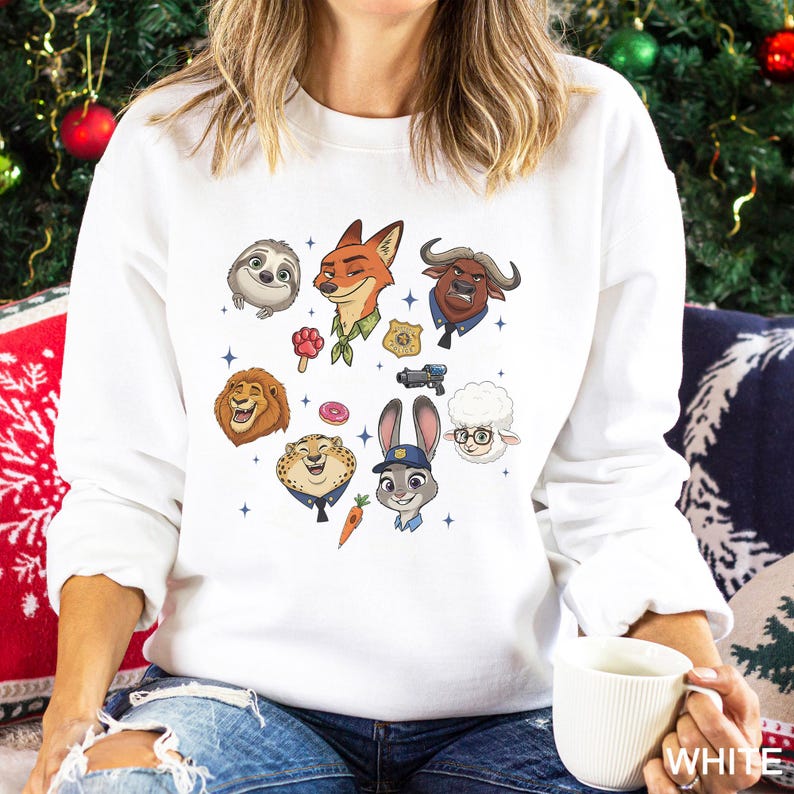 K&ouml;nnte beinhalten: Wei&szlig;es Sweatshirt mit farbenfrohen Cartoon-Illustrationen von Charakteren aus dem Film Zootopia. Das Design zeigt ein Faultier, einen Fuchs, einen L&ouml;wen, einen Geparden, ein Kaninchen, ein Schaf und einen B&uuml;ffel. Das Wort "WHITE" ist auf der Tasse gedruckt.