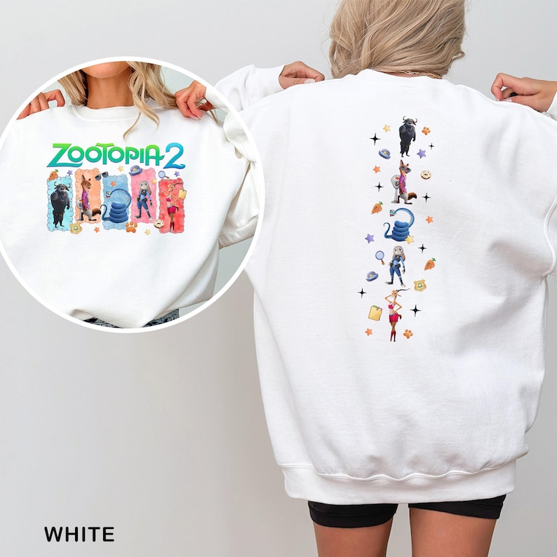 K&ouml;nnte beinhalten: Wei&szlig;es Sweatshirt mit dem Text "ZOOTOPIA 2" in Gr&uuml;n und Blau sowie Zeichentrickfiguren. Die R&uuml;ckseite des Sweatshirts hat ein vertikales Design mit Zeichentrickfiguren und Sternen. Das Wort "WHITE" steht unten.