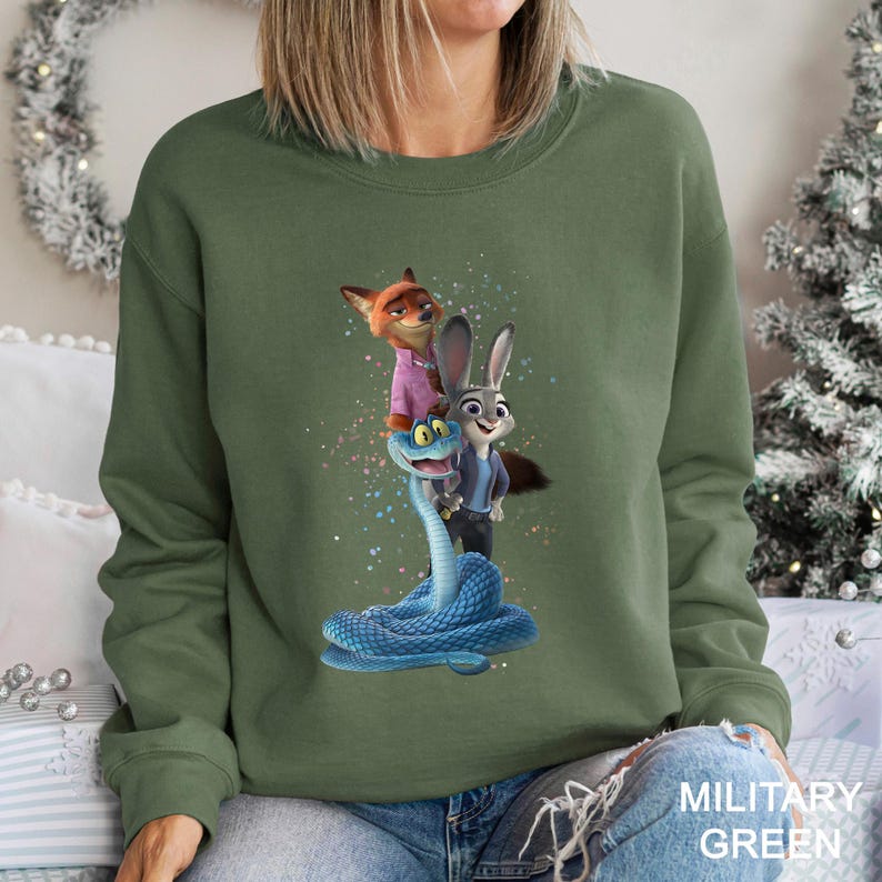 Puede incluir: Sudadera verde militar con un dise&ntilde;o de personajes de dibujos animados. El dise&ntilde;o incluye un zorro, un conejo y una serpiente azul. La sudadera es de cuello redondo.