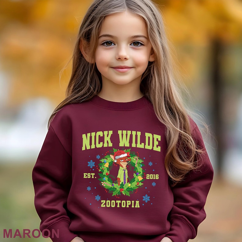 Pu&ograve; includere: Una felpa bordeaux con la scritta "NICK WILDE" in verde, e un'immagine a cartoni animati di Nick Wilde in una ghirlanda natalizia. La felpa include anche il testo "EST. 2016" e "ZOOTOPIA".