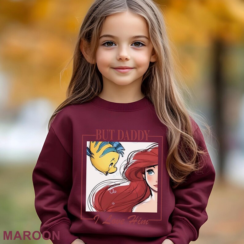 May include: Maroon sweatshirt with a graphic of Ariel and Flounder from The Little Mermaid, and the text "BUT DADDY - I Love Him." The sweatshirt is a solid maroon colour.