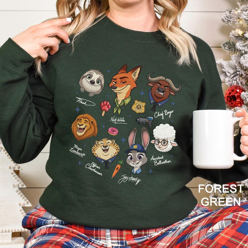 K&ouml;nnte beinhalten: Forstgr&uuml;nes Sweatshirt mit Zeichentrickfiguren aus Zootopia. Das Design umfasst Flash, Nick Wilde, Judy Hopps, Chief Bogo und andere Charaktere. Der Text "FOREST GREEN" befindet sich unten rechts.