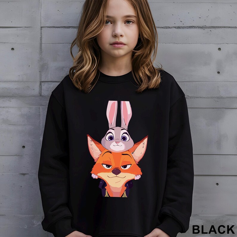 May include: Black sweatshirt featuring a graphic of Judy Hopps the bunny and Nick Wilde the fox from the animated movie Zootopia. The sweatshirt has a crew neck and long sleeves. The word "BLACK" is printed in white at the bottom right.