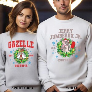 Pu&ograve; includere: Due felpe, una grigio sport e una bianca, con disegni a tema Zootopia. La felpa grigio sport ha "GAZELLE" in rosso, una grafica a ghirlanda e il testo "ZOOTOPIA". La felpa bianca mostra "JERRY JUMBEAUX JR." e una grafica a ghirlanda simile.