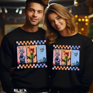 May include: Black sweatshirts featuring a colorful graphic of cartoon characters. The graphic includes a bunny, fox, and snake. The word "BLACK" is printed at the bottom. The sweatshirts are worn by a man and a woman.