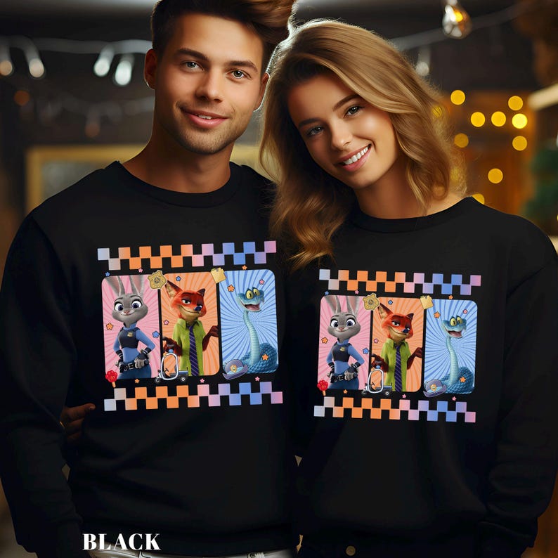 May include: Black sweatshirts featuring a colorful graphic of cartoon characters. The graphic includes a bunny, fox, and snake. The word "BLACK" is printed at the bottom. The sweatshirts are worn by a man and a woman.