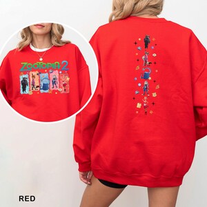 K&ouml;nnte beinhalten: Ein rotes Sweatshirt mit dem Text "ZOOTOPIA 2" und Cartoon-Figuren auf der Vorderseite. Auf der R&uuml;ckseite befindet sich ein vertikales Design aus Cartoon-Figuren und Sternen. Das Wort "RED" ist unten aufgedruckt.