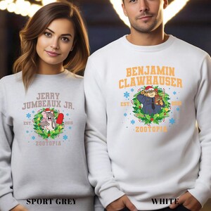 Pu&ograve; includere: Felpe grigio sport e bianche con personaggi di Zootopia. La felpa grigio sport ha il testo "Jerry Jumbeaux Jr." e un'immagine a cartoni animati. La felpa bianca ha il testo "Benjamin Clawhauser". Entrambe hanno il testo "Zootopia".