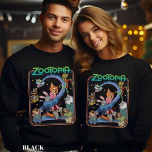 May include: Black sweatshirts featuring the word "Zootopia" in green and blue, with a colorful graphic of characters from the animated film. The sweatshirts are worn by a smiling couple.