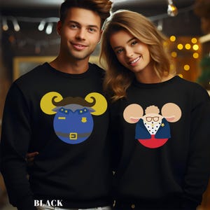 May include: Black sweatshirts with cartoon ram designs. One features a blue police officer ram with gold horns, and the other has a ram dressed in a suit with glasses. The word "BLACK" is printed at the bottom.