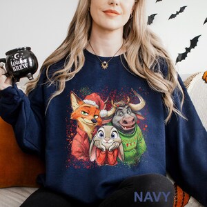 May include: Navy blue sweatshirt featuring a colorful graphic of three animated characters: a fox in a Santa hat, a bunny, and a bull. The sweatshirt has the word "NAVY" printed at the bottom.