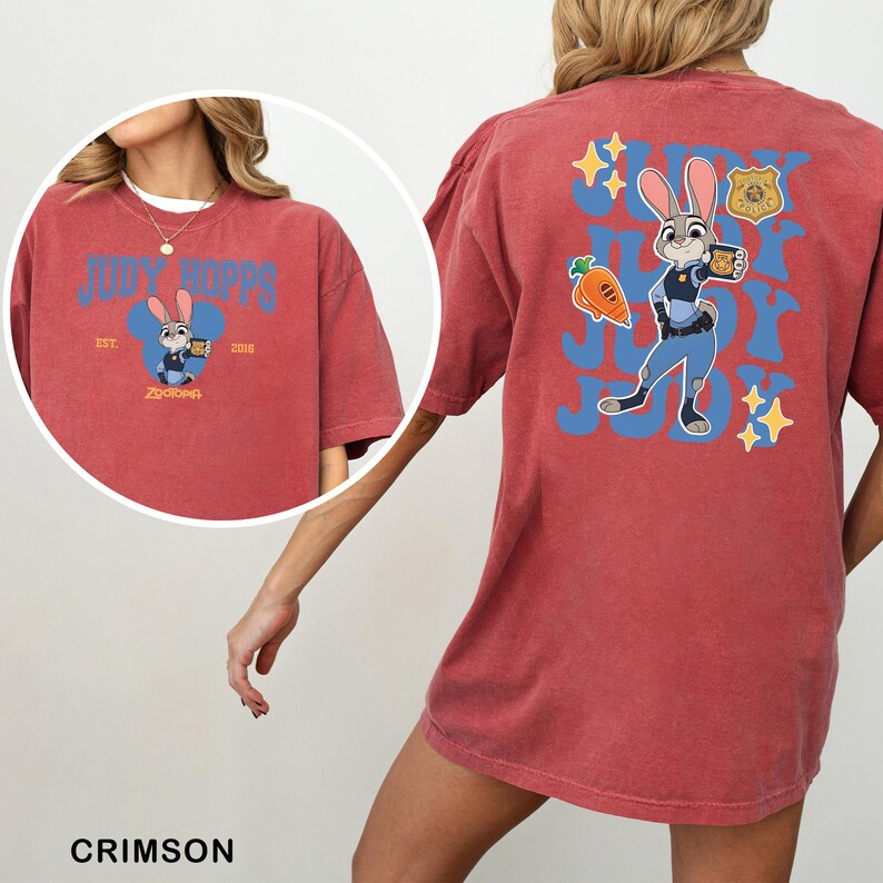 Op de afbeelding: Een karmozijnrood t-shirt met korte mouwen en een afbeelding van Judy Hopps uit Zootopia. De achterkant toont een grote blauwe golvende tekst met Judy Hopps, een wortel en een politiebadge. De voorkant heeft een kleinere Judy Hopps afbeelding.