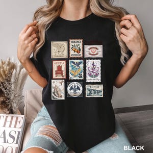 May include: Black t-shirt featuring a collection of postage stamp designs. The stamps showcase various illustrations, including a griffin, a throne, a dragon, and a bridge. The word "BLACK" is printed at the bottom right.