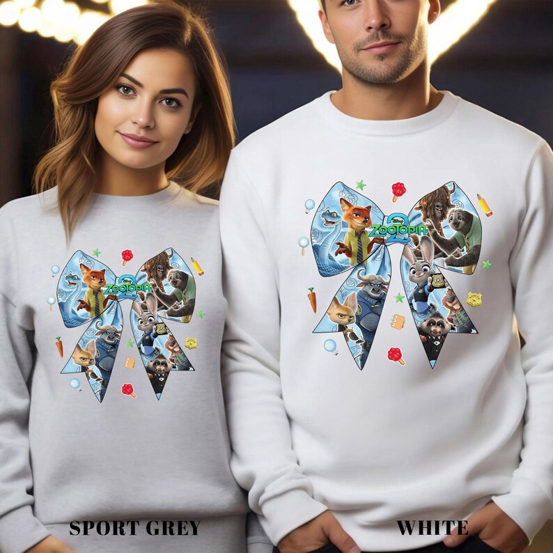 May include: Sport grey and white sweatshirts featuring a large bow design with characters from the animated film "Zootopia." The bow is light blue with various characters and the film's title. The sweatshirts are long-sleeved.