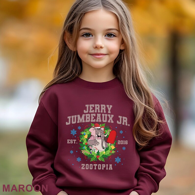 Pu&ograve; includere: Felpa bordeaux con la scritta "JERRY JUMBEAUX JR." sopra una grafica di un elefante e un ghiacciolo, circondati da una ghirlanda. Viene visualizzato anche il testo "EST. 2016 ZOOTOPIA". La parola "MAROON" &egrave; in basso.