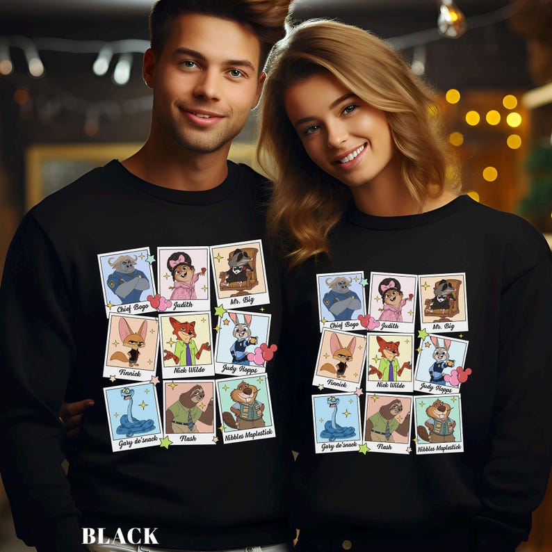 Pu&ograve; includere: Felpe nere con un collage di ritratti di personaggi dei cartoni animati. Ogni ritratto &egrave; in una cornice in stile polaroid con i nomi dei personaggi sottostanti. La parola "BLACK" &egrave; stampata in basso nell'immagine.
