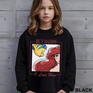 May include: Black sweatshirt with a graphic of Ariel and Flounder from The Little Mermaid, and the text "BUT DADDY I Love Him". The sweatshirt is black.