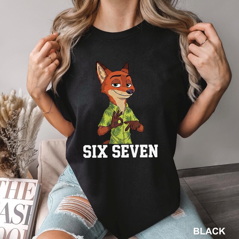 May include: Black t-shirt with a cartoon fox wearing a green Hawaiian shirt. The text "SIX SEVEN" is printed in white block letters below the character. The shirt is a solid black colour.
