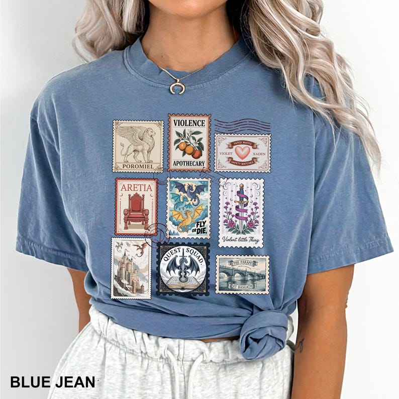 May include: Blue jean colored t-shirt featuring a collection of postage stamp designs. The stamps depict various illustrations, including a griffin, a throne, a dragon, and text such as "VIOLENCE" and "QUEST SQUAD".