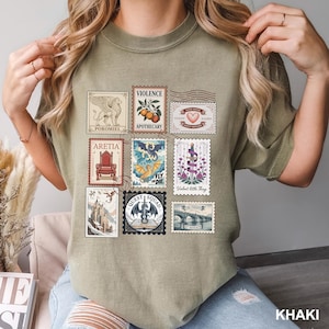 May include: Khaki-colored t-shirt featuring a collection of vintage-style postage stamps with various illustrations and text. The stamps include images of a griffin, a dragon, a bridge, and text such as "Violence" and "Quest Squad".