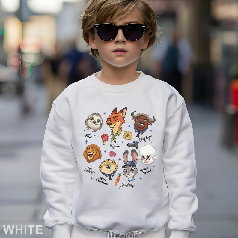 K&ouml;nnte beinhalten: Wei&szlig;es Sweatshirt mit Zeichentrickfiguren aus dem Film Zoomania. Das Design umfasst Bilder von Flash, Nick Wilde, Chief Bogo, Judy Hopps und anderen. Das Wort "WHITE" ist unten aufgedruckt.