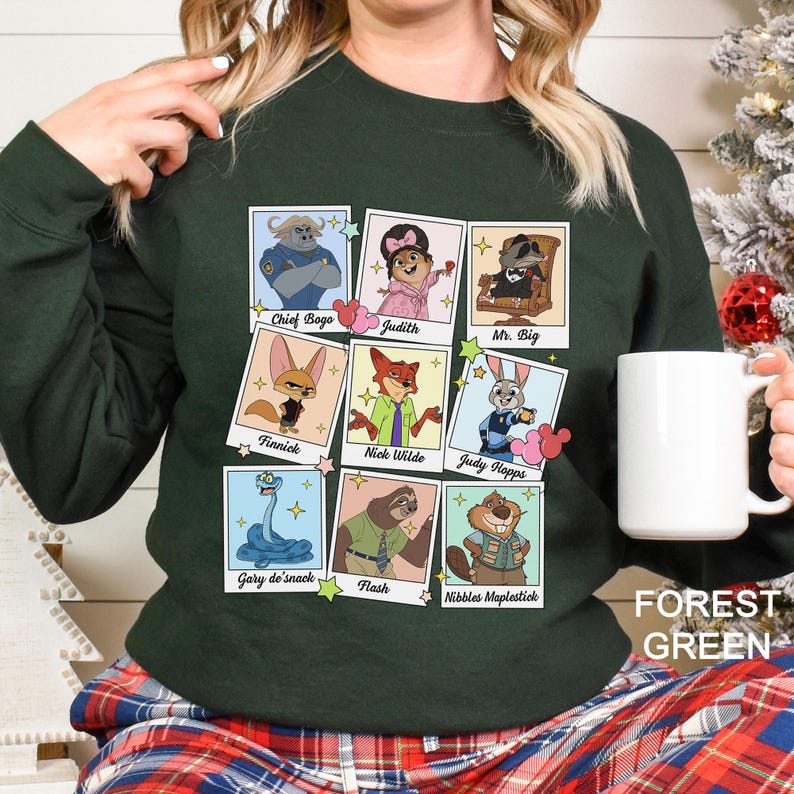 Pu&ograve; includere: Felpa verde foresta con un collage di ritratti di personaggi dei cartoni animati. I personaggi includono Chief Bogo, Judith, Mr. Big, Finnick, Nick Wilde, Judy Hopps, Gary de'snack, Flash e Nibbles Maplestick. Il testo "FOREST GREEN" &egrave; stampato in basso a destra.